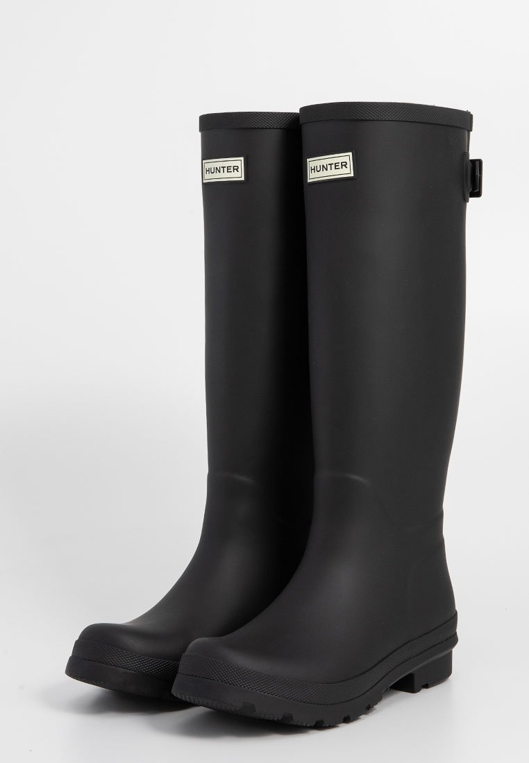 Schwarze Gummistiefel mit matter Oberfläche, bis zur Mitte der Waden, strukturierte Sohlen und Logoakzente an den oberen Seiten.