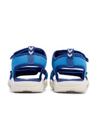 Niebieskie sandały z otwartym tyłem, z siateczkową cholewką, kontrastującymi niebieskimi paskami i białą gumową podeszwą. Posiadają regulowane zapięcia oraz teksturowaną wkładkę.