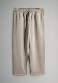 Gai bēša sporta bikses ar elastīgu jostu un kaklasaistītiem aukliņām, ar divām sānu kabatām un gludu, mīkstu tekstūru.