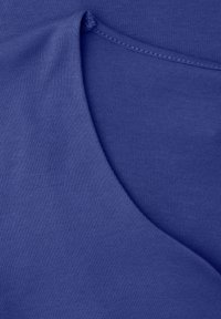 Primer plano de una tela azul que muestra un borde doblado y una costura detallada a lo largo de la costura.