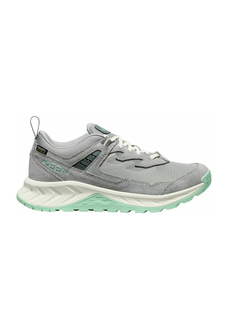 Scarpa sportiva grigia con materiali in rete e suede, lacci bianchi e suola verde menta. Presenta motivi textured e una linguetta sul tallone.