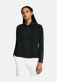 Schwarze Zip-Jacke aus leichtem Material mit körperbetontem Design. Verfügt über weiße Streifen entlang der Ärmel und einen Stehkragen.