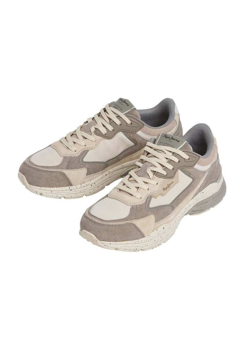 Beige en grijze sneakers met een mix van suede en mesh materialen, dikke witte spikkelzool, gevoerde kraag en contrasterende veters.