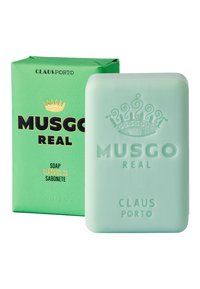 Grüne Verpackung mit schwarzem und goldfarbenem Text zeigt ein halbtransparenter mintgrüner Seifenblock, der mit "MUSGO REAL" und einem Kronendesign geprägt ist.