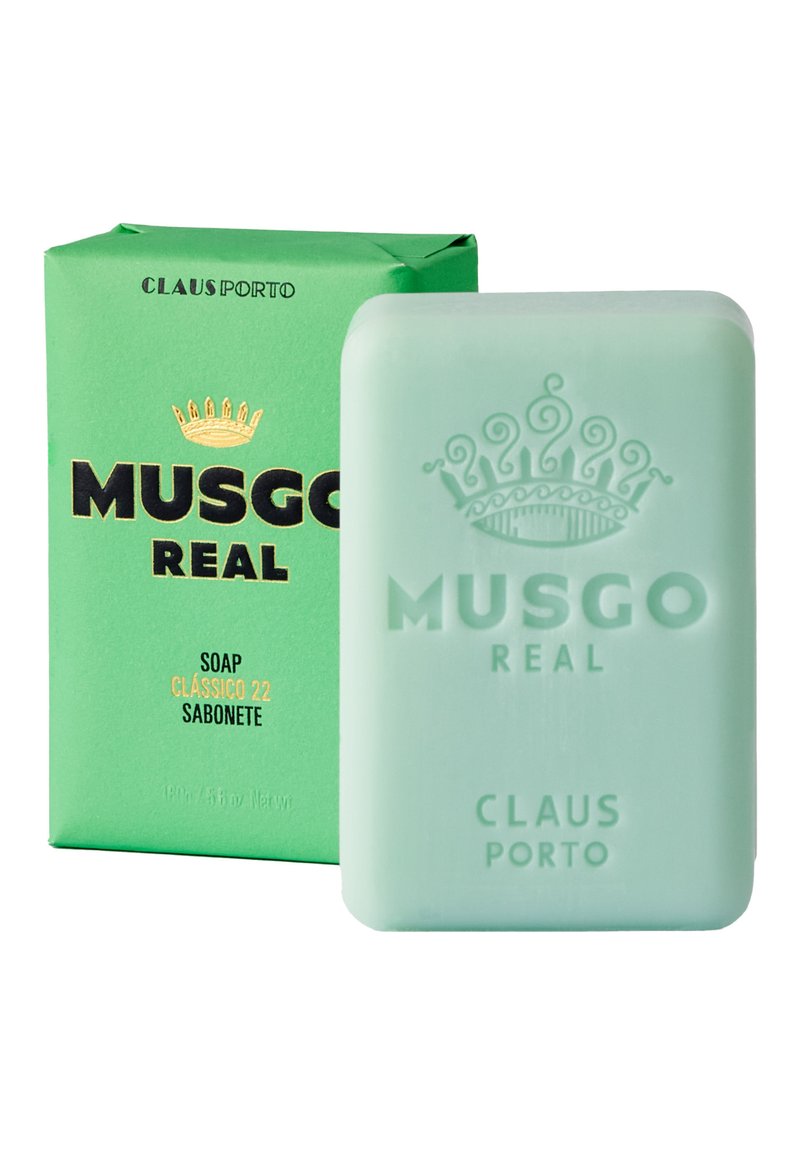 Grüne Verpackung mit schwarzem und goldfarbenem Text zeigt ein halbtransparenter mintgrüner Seifenblock, der mit "MUSGO REAL" und einem Kronendesign geprägt ist.