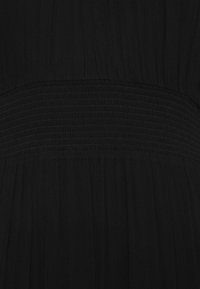 Czarna sukienka z marszczonym pasem, zwiewną plisowaną tkaniną oraz lekkim, teksturowanym materiałem zapewniającym gładki wygląd.