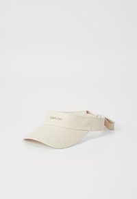 Beige solhatt med bred skjerm, laget av mykt stoff. Har en justerbar reim og brodert logo på frontbåndet.