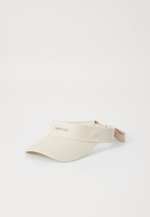 Beige zonneklep met een brede rand, gemaakt van zacht materiaal. Voorzien van een verstelbare band en een geborduurd logo op de voorzijde.