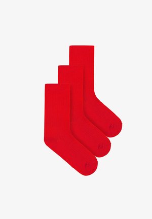 Trzy jaskrawoczerwone, prążkowane skarpetki za kostkę ułożone na białym tle, częściowo nakładające się na siebie.