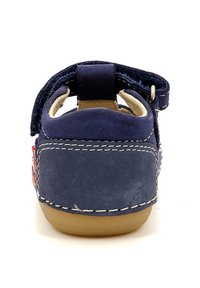 Scarpa in suede blu navy con cinturino a strappo, tallone rotondo, cuciture bianche e suola in gomma beige. Presenta un accento colorato sul lato.