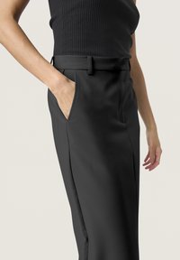 Pantaloni neri su misura con una texture liscia, dotati di tasche laterali, una vita strutturata e una vestibilità a gamba dritta.