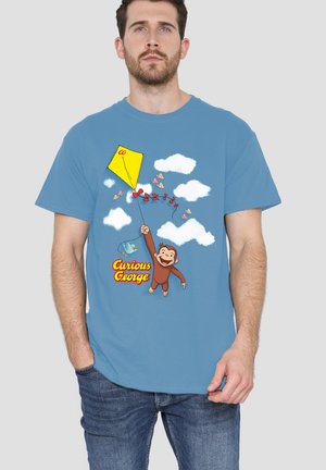 Man wearing blue t-shirt with Curious George holding a red kite string, flying among clouds, butterflies, and a blue bird.