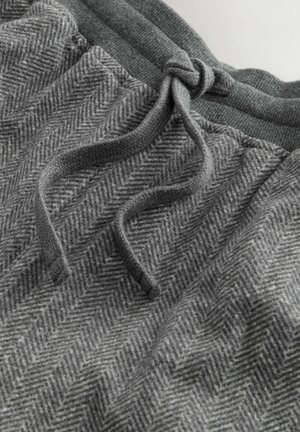 Grå joggers i texturerat tyg med herringbone-mönster, med en elastisk midja och dragsnodd för justering av passformen.