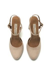 Zapatos de tacón alto en color nude beige con una textura de ante suave, punta afilada y una correa ajustable en el tobillo.
