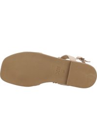 Suela de sandalia de goma beige con textura acanalada. Presenta una correa ajustable y detalle de hebilla. Marcada con la marca "Xti" y tamaño "38".