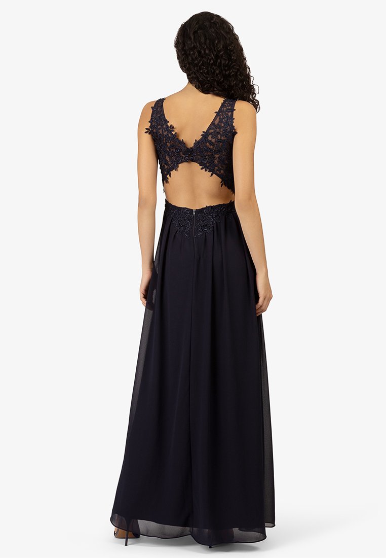 Granatowa wieczorowa sukienka z dopasowanym gorsetem, koronkowymi detalami w kształcie fal oraz zwiewnym dołem. Otwarty tył z zapięciem na zamek.