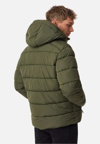 Zielona kurtka puchowa w odcieniu oliwkowym, z poziomymi przeszyciami, przymocowanym kapturem i zamykanymi na zamek bocznymi kieszeniami, przedstawiona z tyłu.