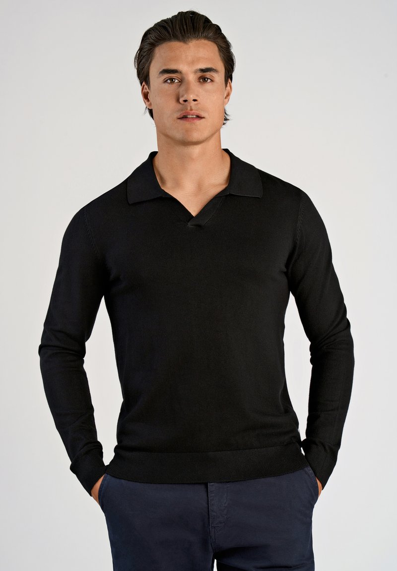 Czarny długi rękaw polo sweter z dekoltem w serek, ściągaczami przy mankietach i u dołu. Materiał wydaje się gładki i miękki, zaprojektowany z myślą o dopasowanej sylwetce.