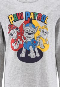 Grauer Sweatshirt mit "Paw Patrol"-Cartoonfiguren, ausgestattet mit bunten Designs von Hunden in Rot-, Blau- und Gelbtönen auf dem Stoff.