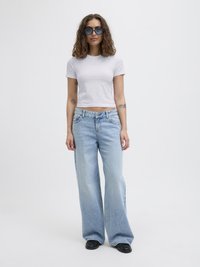 Hvit tettsittende t-skjorte, lyseblå vide jeans, og svarte sko. Krøllete hår, blå solbriller. Minimalistisk design, myke teksturer, uformell stil.