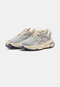 Scarpe da ginnastica grigie con tomaia testurizzata, dettagli color crema e suola viola. Presentano un design con lacci e un colletto imbottito per il comfort.