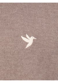 Bruine sweaterstof met een gebreide textuur en een wit geborduurd kolibrilogo aan de linkerkant.