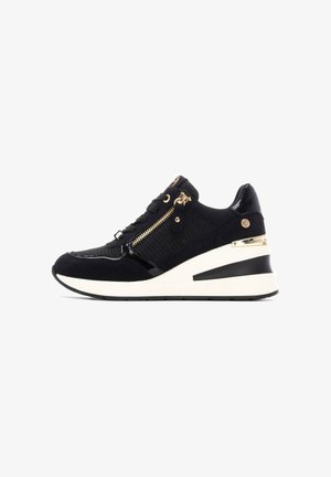Zapatillas cuña negras con una combinación de texturas mate y charol, con herrajes dorados, un zipper lateral y una suela blanca acolchada.