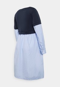 Navy cotton top with short sleeves, layered over a light blue striped dress. Features a rounded neck and buttoned cuffs.