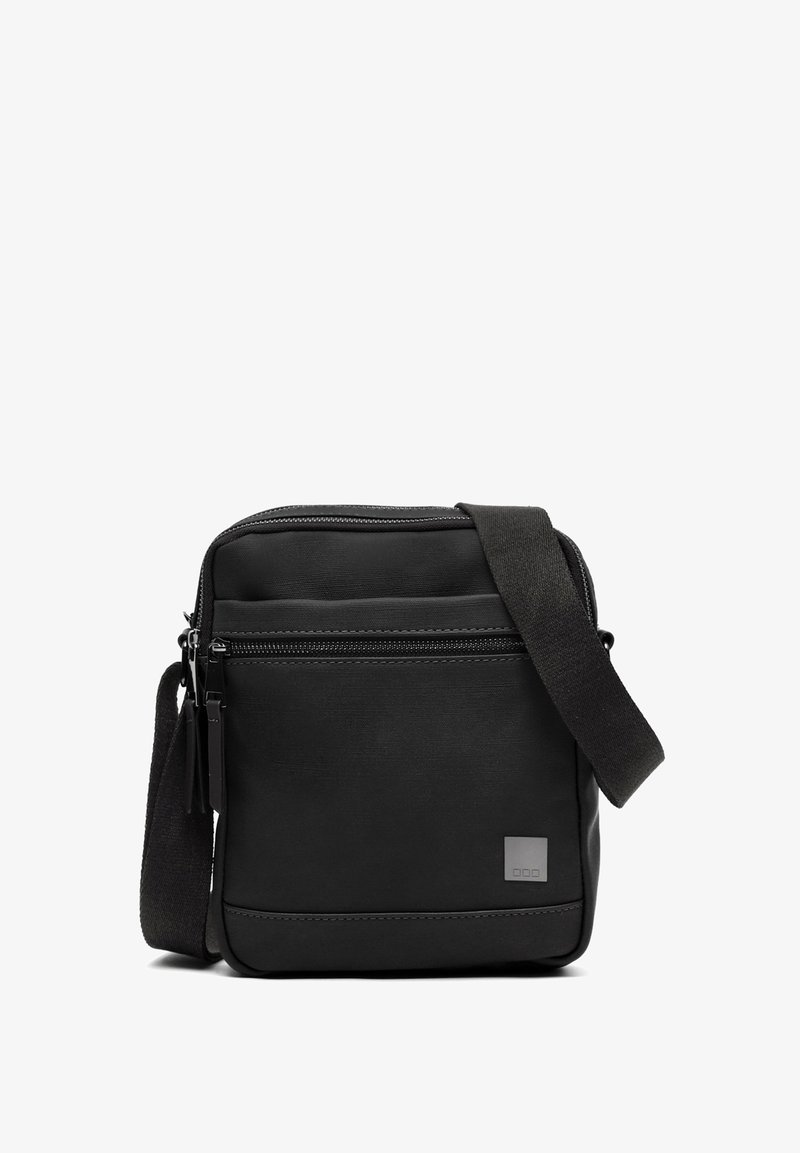 Čierna crossbody taška vyrobená z hladkého materiálu, s predným vreckom na zips a nastaviteľným popruhom. Minimalistický dizajn s jemným brandovaním.