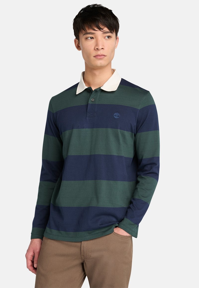 Camisa polo de manga larga con rayas horizontales en verde oscuro y azul marino, un cuello color crema y un pequeño logotipo en el pecho.
