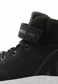 Zwarte hoge schoen met een gladde stofupper, verstelbare band, metalen veterogen en een textuur outsole voor grip. Voorzien van branding.