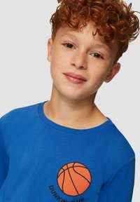 Blaues langärmliges Baumwollhemd mit einem schwarzen Basketball-Graphic und dem Text "DUNKIN CLUB". Glatte Textur, runder Halsausschnitt.