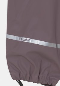 Maroon waterproof jacket with a silver reflective stripe and elasticated hem. Features "Celavi" branding in a dark purple. Smooth texture.