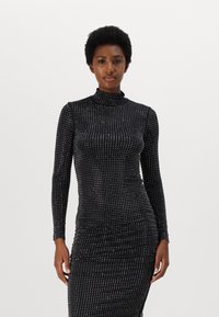 Long-sleeve black dress made from a stretchy material, featuring a raised dotted pattern and a high neck. Form-fitting silhouette.