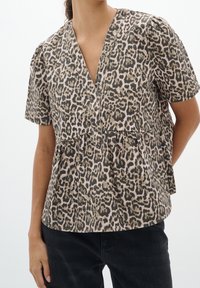 Top corto a maniche corte con stampa leopardata in beige e nero, con scollatura a V e stile peplum arricciato, realizzato in tessuto morbido.
