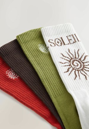 Négy pár bordázott zokni piros, barna, zöld és fehér színben. A fehér zoknin barna színű "SOLEIL" felirat és egy napfény dizájn található.