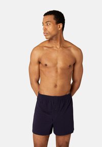 Navy blue boxer shorts with an elastic waistband and a front button. Fabric appears smooth with a simple design, no visible patterns.