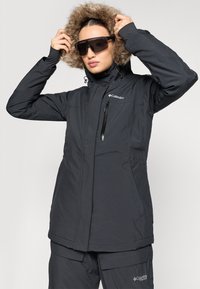 Črna izolirana parka z usnjeno kapuco in žepi na zadrgo, ki se ponaša z elegantnim dizajnom in gladko teksturo tkanine.