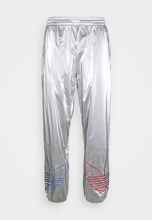 Srebrne metaliczne spodnie dresowe z elastycznym pasem i czerwono-niebiesko-czarnymi wyhaftowanymi logo Adidas trefoil w pobliżu dolnych krawędzi.