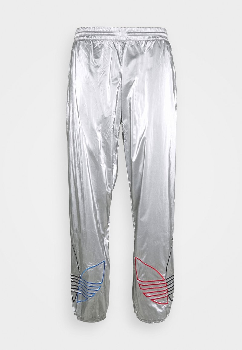 Silberne metallische Jogginghosen mit elastischem Bund und roten, blauen und schwarzen bestickten Adidas Trefoil-Logos nahe den unteren Säumen.