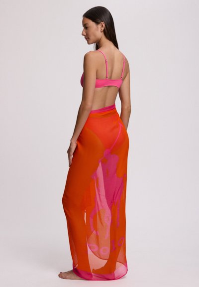Ροζ τοπ μπικίνι με λεπτές τιράντες, συνδυασμένο με διαφανή πορτοκαλί φούστα που φτάνει μέχρι τους αστραγάλους, με ροζ γραφικό σχέδιο και λογότυπο, με ρέουσα υφή.