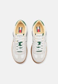 Zapatillas blancas con acentos verdes. Presentan materiales de cuero y ante, puntera redonda, cierre con cordones y suela de goma. Logo en la lengüeta.