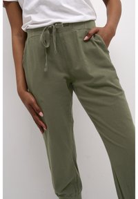 Olijfgroene, lichtgewicht katoenbroek met een elastische tailleband, trekkoord en zijzakken. Tapered pijpen met een relaxte pasvorm.