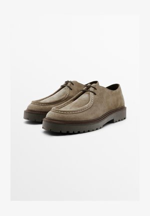 Wildlederschuhe in einem gedämpften Braunton mit kontrastierenden hellbraunen Akzenten, rund zulaufender Zehenpartie und dicken, strukturierten Gummisohlen.