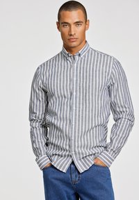 Camisa de botones de rayas en gris claro y azul marino, tela de mezcla de algodón, mangas largas, cuello clásico, con dobladillo recto y puños doblados.