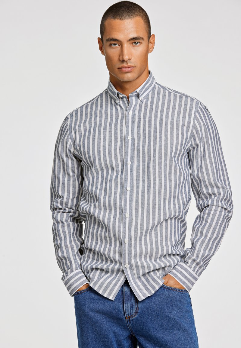 Camisa de botones de rayas en gris claro y azul marino, tela de mezcla de algodón, mangas largas, cuello clásico, con dobladillo recto y puños doblados.