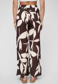 Pantalons à jambes larges en tissu marron avec un motif de feuilles blanches, dotés d'une taille élastique, d'une texture lisse et de détails minimes.