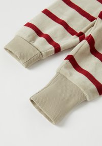 Puuvillane särk, mille varrukas on ribastatud beežide mansettidega, mustriga, kus on horisontaalsed punased triibud heleda beeži tausta peal. Pehme tekstuur, casual disain.