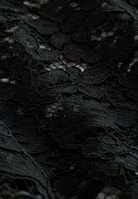Black lace fabric featuring intricate floral patterns with layered textures, showcasing a mix of solid and open weave sections.