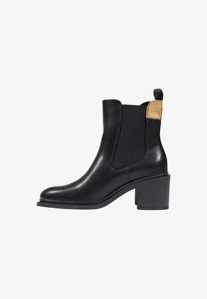 Bottines en cuir noir avec un bout rond, des panneaux latéraux élastiques et un accent beige contrastant à l'arrière. Talon carré. Texture lisse.
